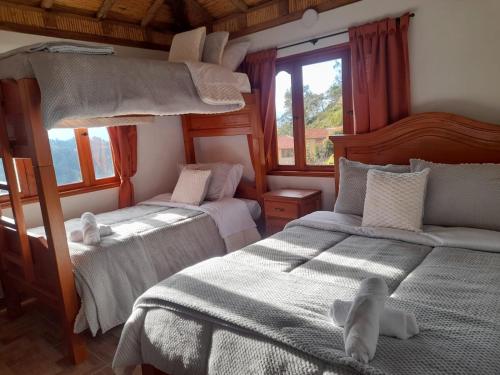 two beds in a room with windows and two bedsitures at Casa Bahu Campestre in Villa de Leyva