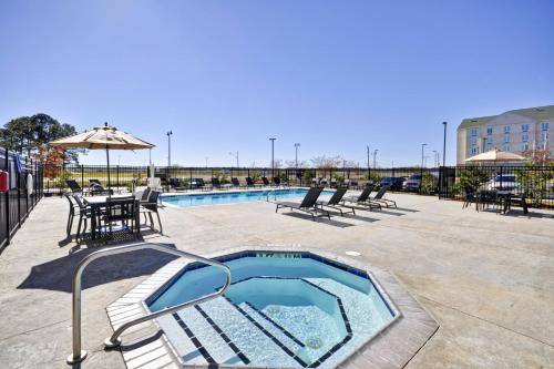 a swimming pool with chairs and a table and an umbrella at Residence Inn by Marriott Gulfport-Biloxi Airport in Gulfport