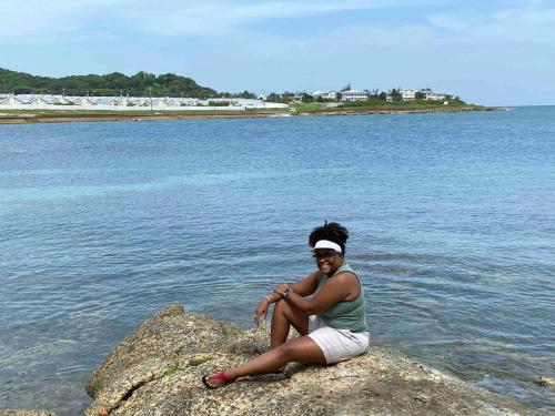 a woman sitting on a rock in the water at VillaMerissa Ocenpointe in Point