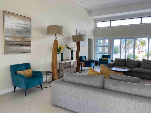 a living room with a gray couch and blue chairs at VillaMerissa Ocenpointe in Point