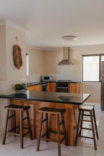 a kitchen with a counter and two bar stools at Pet Friendly Townhouse in Geraldton