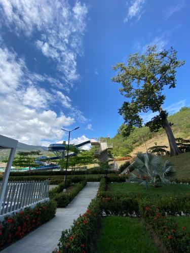 a walkway in a park with flowers and a tree at Luxury Apartment Citadela de Sole Santa fe de Antioquia in Santa Fe de Antioquia