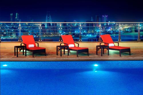 a group of chairs sitting next to a pool at night at Marriott Executive Apartments Manama, Bahrain in Manama