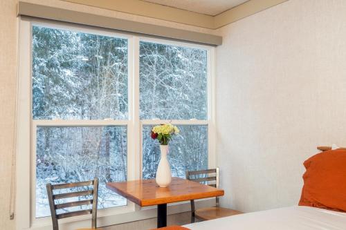 a vase of flowers on a table in front of a window at Mountainside Inn 403 by Alpine Lodging Telluride in Telluride