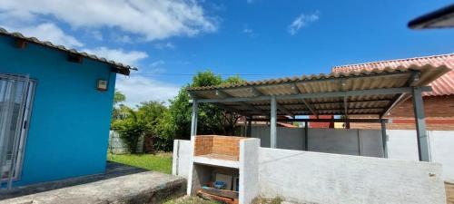 a blue house with a wooden roof and a concrete wall at Yamini - Barra del Chuy in Barra del Chuy