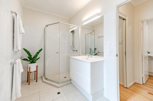 a white bathroom with a shower and a sink at The Sunshine Beach Luxe Coastal Retreat in Sunshine Beach