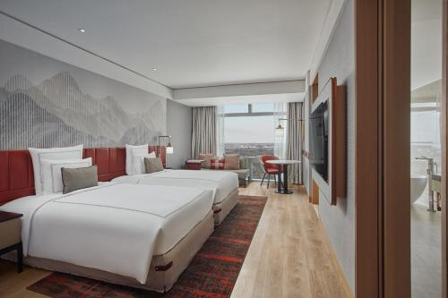 a hotel room with two beds and a television at Swissôtel Clark Philippines in Clark