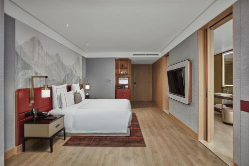 a bedroom with a large white bed and a television at Swissôtel Clark Philippines in Clark
