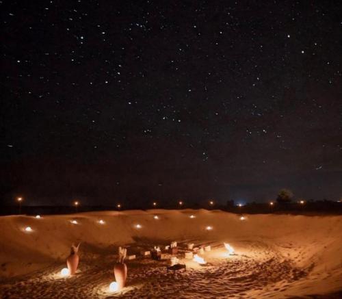 a group of people in the sand at night at Excellent Desert Safari camp in Sām