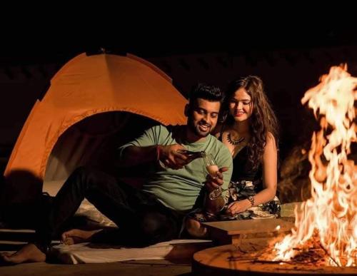 a man and a woman sitting next to a fire at Excellent Desert Safari camp in Sām