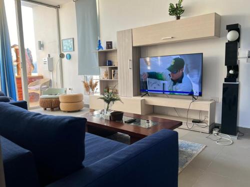 a living room with a blue couch and a flat screen tv at 1BR with private Heated Jacuzzi at Sholan Elgouna in Hurghada