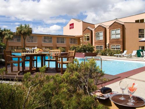 a patio with a table and chairs next to a pool at Mercure Queenstown Resort in Queenstown