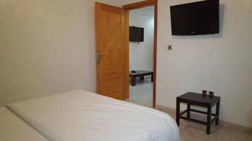 a bedroom with a bed and a television on the wall at Hôtel Prestige in Nouadhibou