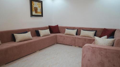 a living room with a brown couch with pillows at Hôtel Prestige in Nouadhibou