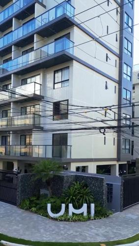 a tall white building with a sign in front of it at UMI Flat Intermares 4 Andar in Cabedelo