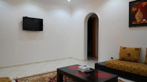 a living room with a couch and a tv on a wall at Hôtel Prestige in Nouadhibou