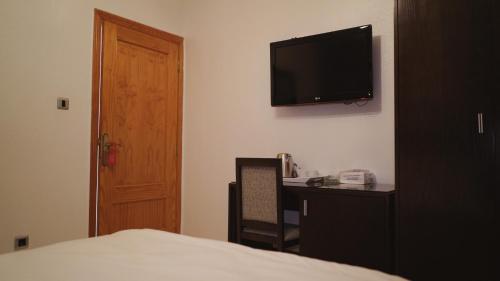 a bedroom with a bed and a desk and a television at Hôtel Prestige in Nouadhibou