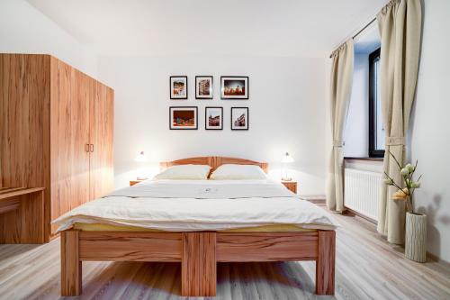 um quarto com uma grande cama de madeira e 2 janelas em Penzion Královská Cesta em Brno