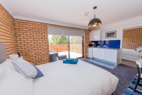a bedroom with a white bed and a brick wall at Sea Shanty in Bicheno