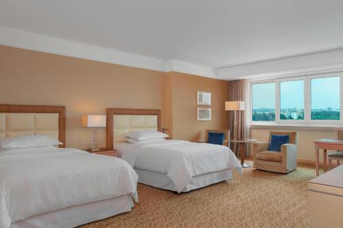 克拉布德品斯Sheraton Club des Pins Resort的大型酒店客房,配有两张床和椅子