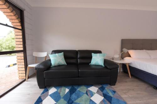 a living room with a black couch and a bed at Anchors Away in Bicheno