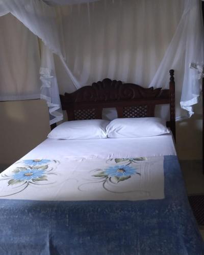 a bed with a white comforter with blue flowers on it at Casa Macacos in Porto Seguro