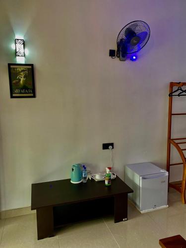 a living room with a table and a fan on the wall at Cozy Homestay Waterfall Road Ella in Ella