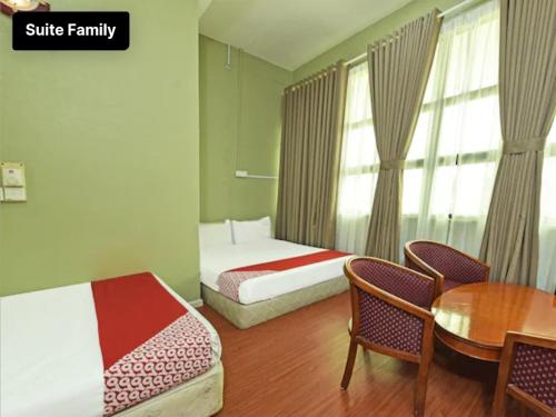 a bedroom with two beds and a table and chairs at Hotel azimah in Pasir Puteh