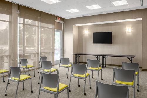 a waiting room with chairs and a table and a tv at SpringHill Suites by Marriott Savannah Richmond Hill in Richmond Hill