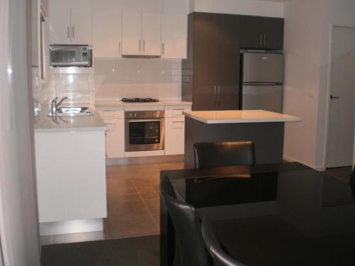 cocina con armarios blancos, fregadero y encimera en King Street Apartments, en Warrnambool