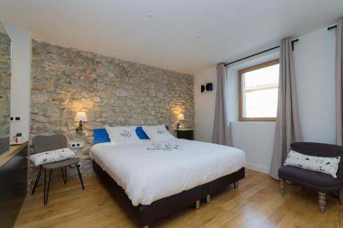 a bedroom with a large bed and a stone wall at Le Petit Chalande in Autrans