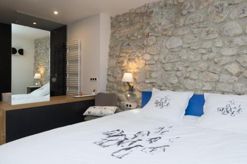 a bedroom with a large bed and a stone wall at Le Petit Chalande in Autrans