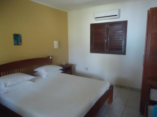a bedroom with a white bed and a window at Ekoara Bangalos in Jacumã