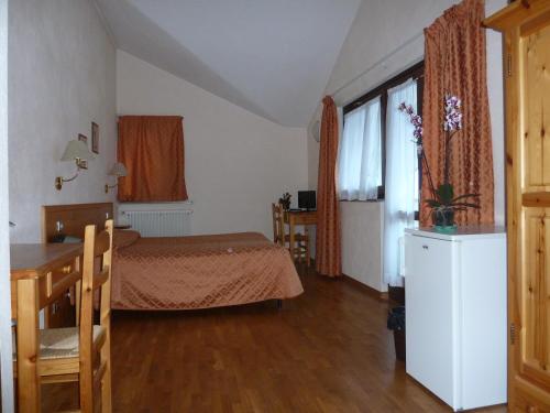 a bedroom with a bed and a table and a window at Hotel Le Verger in Châtillon