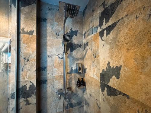 a shower in a bathroom with a stone wall at Moi Induruwa by DBI in Bentota