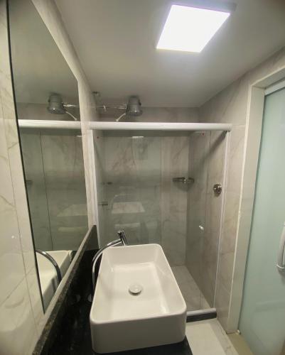 a bathroom with a white sink and a shower at Pousada do Braga in Cabo Frio