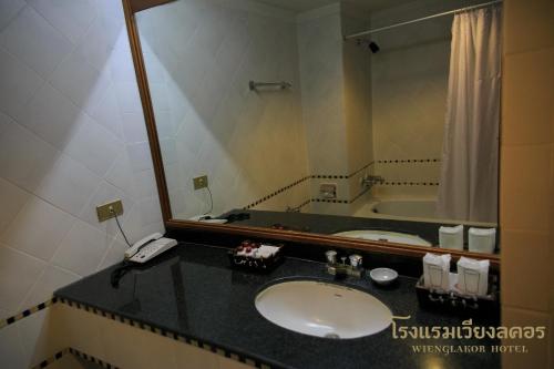 baño con lavabo y espejo grande en Wienglakor Hotel Lampang en Lampang