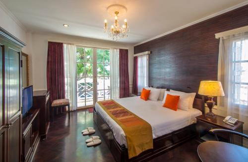 a bedroom with a large bed and a television at Le Bouton D'or Boutique Hotel in Thakhek
