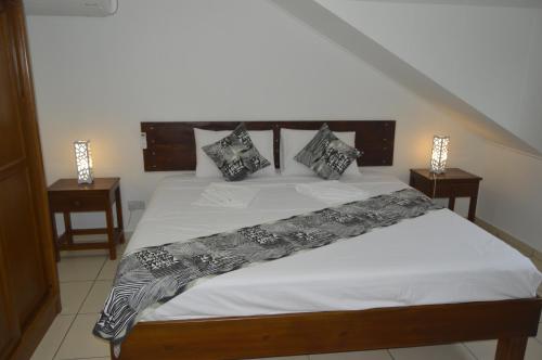 um quarto com uma cama com lençóis brancos e almofadas em Chez Payet Airport Guesthouse em Pointe Larue