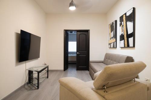 a living room with a couch and a tv at Refugio Elegante y Equipado en Zona Dorada in Mexicali