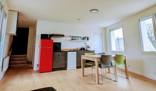 une cuisine avec une table et un réfrigérateur rouge dans l'établissement Appartement 2 chambres 4 personnes, à Sainte-Reine-de-Bretagne
