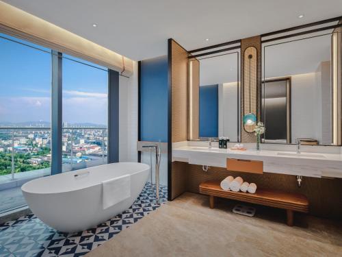 a bathroom with a tub and a large window at Hotel Indigo Yantai Golden Coast by IHG in Yantai