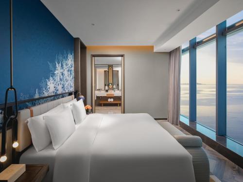 a bedroom with a large white bed and a large window at Hotel Indigo Yantai Golden Coast by IHG in Yantai