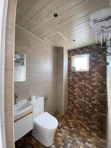 a bathroom with a toilet and a brick wall at CS Junction Point - Special Day Room SDR in Kuala Pilah