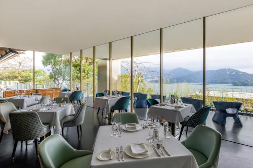 a restaurant with white tables and chairs and windows at Grand Hilai Sun Moon Lake in Yuchi