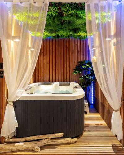 Cette chambre comprend une baignoire et des rideaux. dans l'établissement Secret Lovely, à Seysses