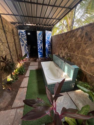 a bathroom with a bath tub and some plants at Coco inn Goa in Candolim