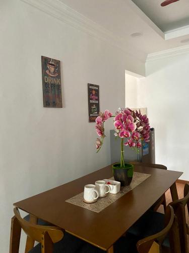 a dining room table with a vase of flowers on it at The Fortune Homestay in Kota Kinabalu