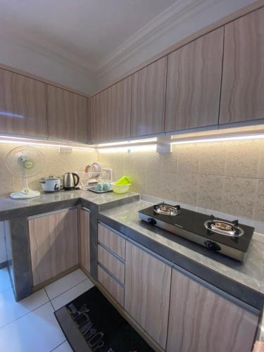 a kitchen with wooden cabinets and a stove top oven at The Fortune Homestay in Kota Kinabalu