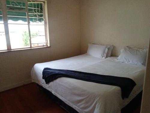 a bedroom with a large white bed with a window at Afro Africa Poperties in Pietermaritzburg